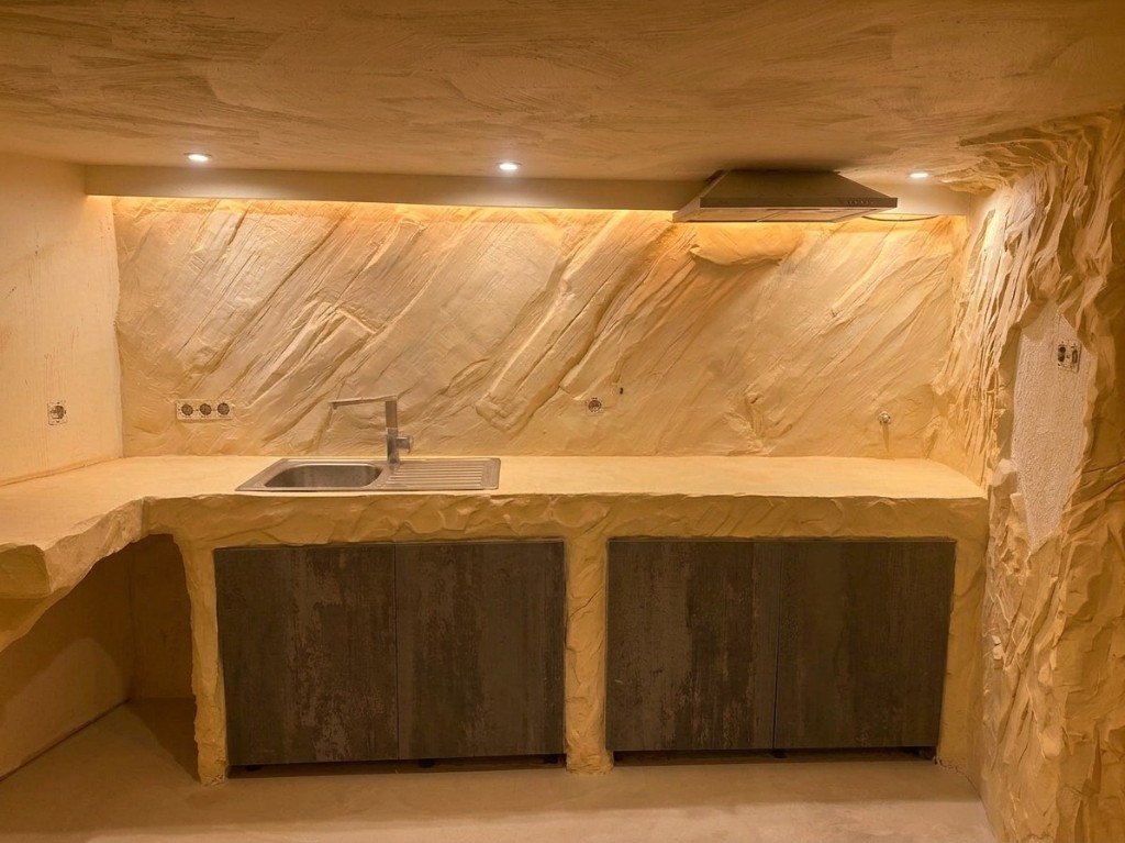 Cozinha com parede, bancada e teto em efeito rocha